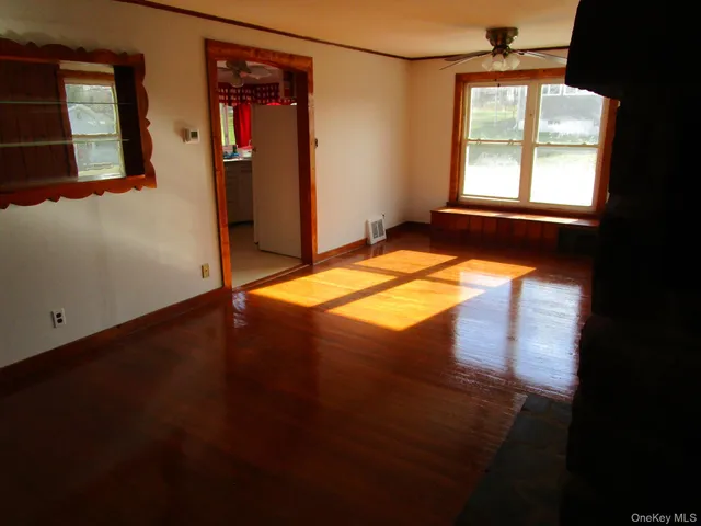 an empty room with wooden floor fireplace and windows