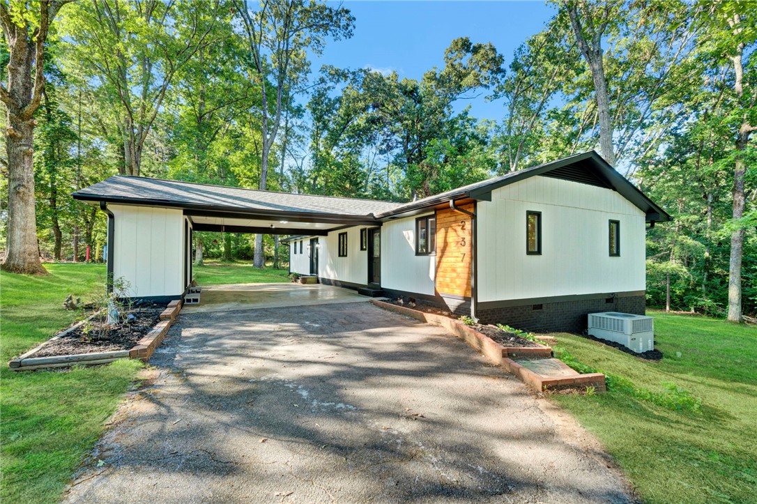 237 Earle Road Central, SC 29630 - Photo 2 of 24 A well-maintained home nestled among mature trees offers a private driveway and attached carport.