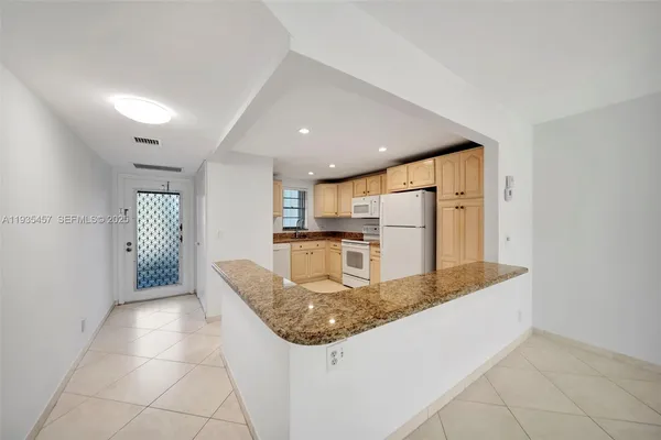 a kitchen with stainless steel appliances granite countertop a sink and a refrigerator