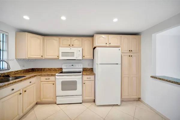 a kitchen with white cabinets and white stainless steel appliances and refrigerator