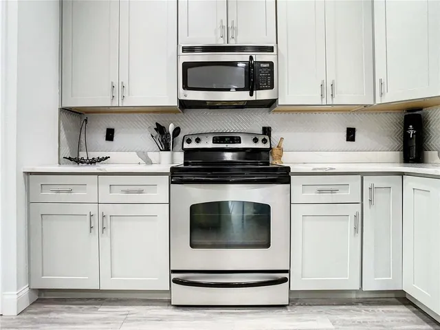 a kitchen with white cabinets and appliances