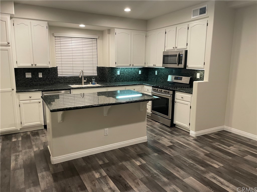 a kitchen with stainless steel appliances granite countertop a stove a sink and a microwave
