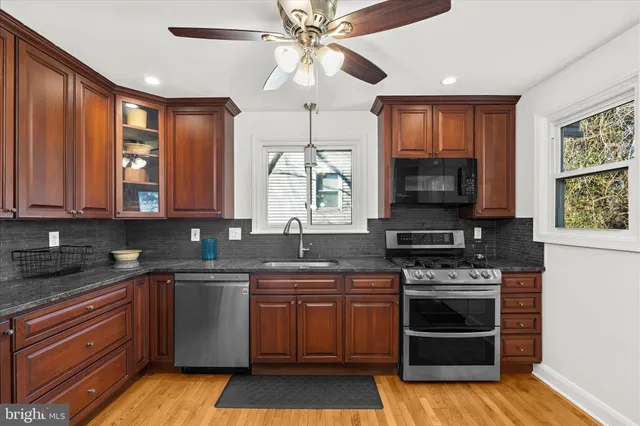 a kitchen with stainless steel appliances granite countertop a refrigerator a stove and a microwave oven with wooden floor