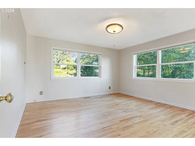 a view of a hallway with wooden floor and a bathroom