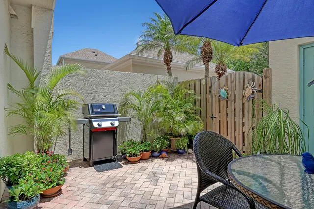 a backyard of a house with table and chairs under an umbrella