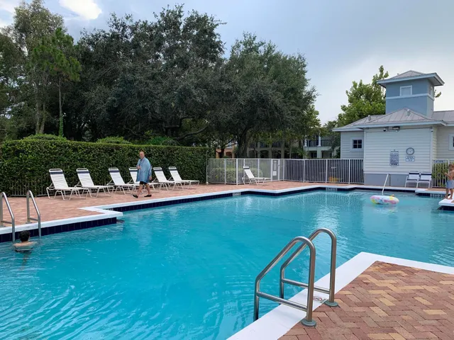 a view of a swimming pool and lounge chairs in back yard