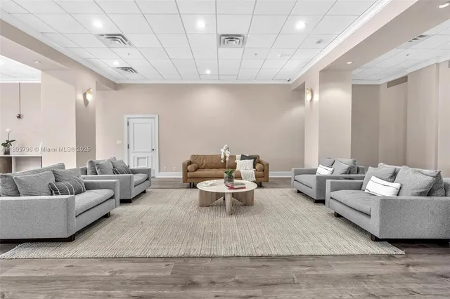 a living room with couches a coffee table and chairs with wooden floor