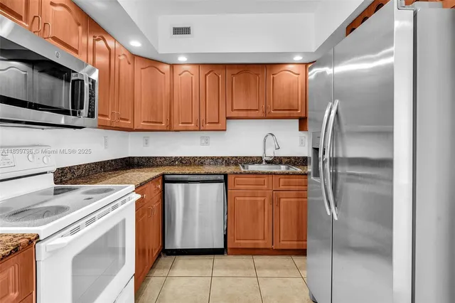 a kitchen with stainless steel appliances granite countertop a refrigerator oven a sink dishwasher and a microwave oven with cabinets