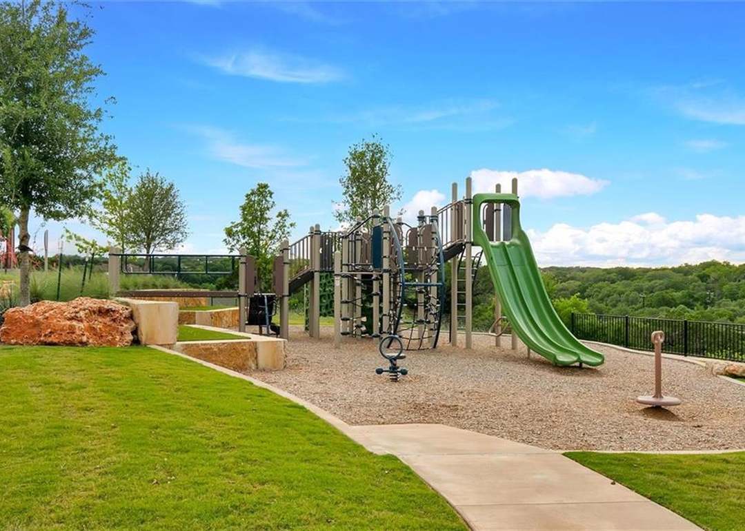 208 Wolf Springs Road Georgetown, TX 78628 - Photo 31 of 32 A vibrant playground set against a backdrop of lush green trees, perfect for active children.