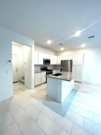 a large kitchen with a large counter top stainless steel appliances and cabinets