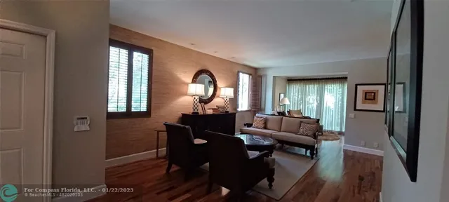 a living room with furniture and a large mirror next to a window