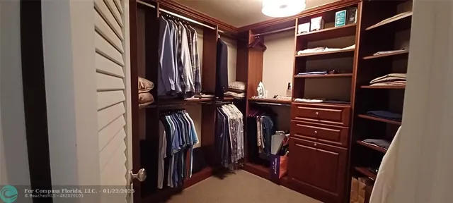 a view of walk in closet with clothes and shoes