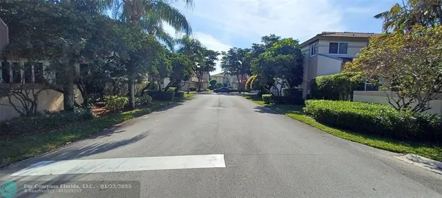 a view of a street with potted plants and a building in the background