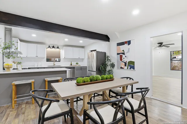 a kitchen with stainless steel appliances kitchen island granite countertop a dining table chairs and white cabinets