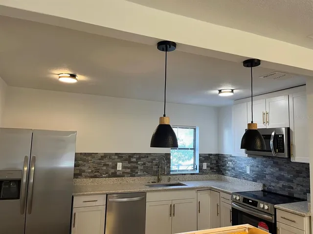 a kitchen with stainless steel appliances granite countertop a sink a stove and a refrigerator