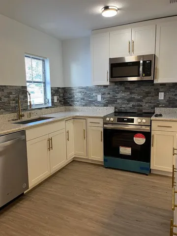 a kitchen with stainless steel appliances granite countertop a stove a sink and a microwave