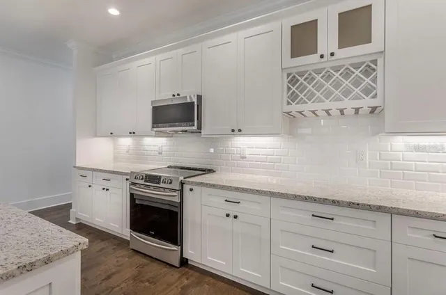 a large kitchen with stainless steel appliances granite countertop a sink a stove and a refrigerator