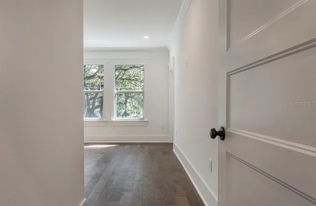 a view of an empty room with wooden floor and a window