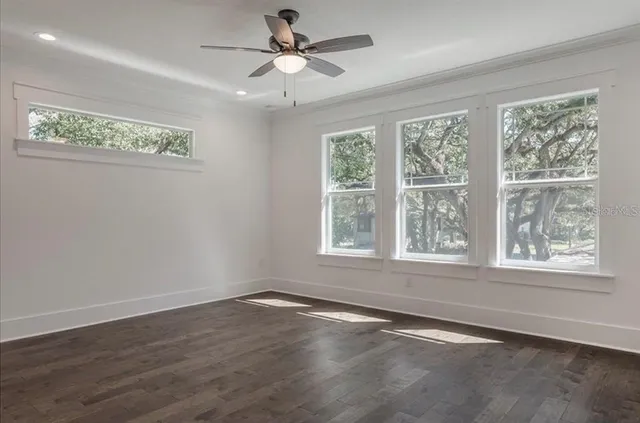 an empty room with wooden floor and fan