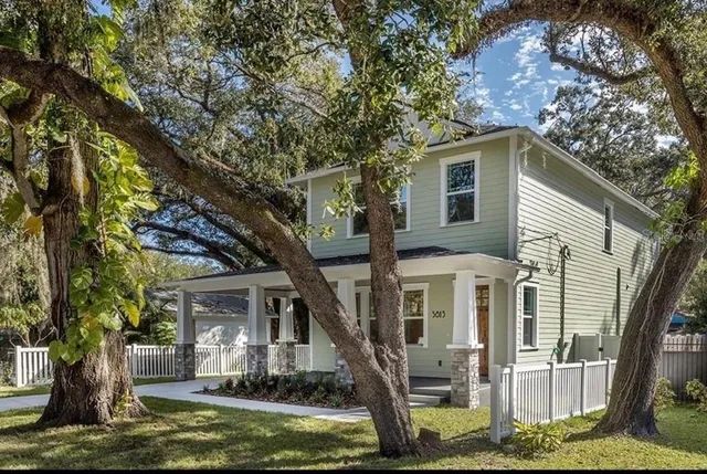 a view of a house with a small yard and large tree