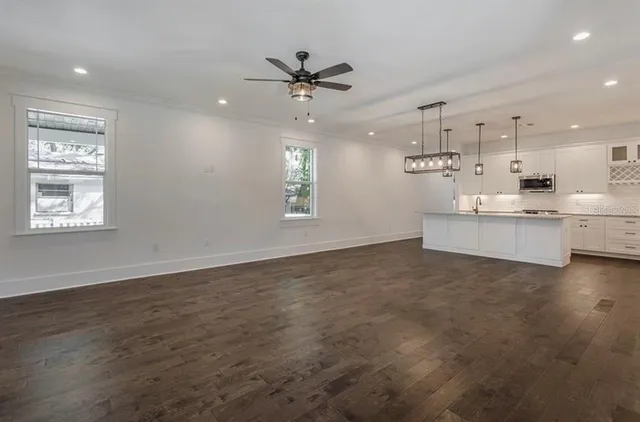 a view of a kitchen with a sink dishwasher a kitchen island with wooden floor and a window