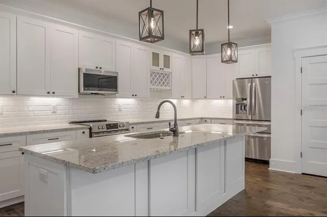 a kitchen with granite countertop white cabinets and stainless steel appliances