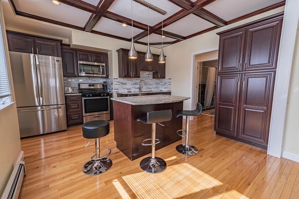 12 Jones Avenue, Unit 1 Chelsea, MA 02150 - Photo 2 of 17 a kitchen with stainless steel appliances kitchen island granite countertop a refrigerator stove microwave and sink