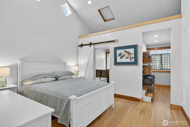 a bedroom with a bed next to a window with wooden floor