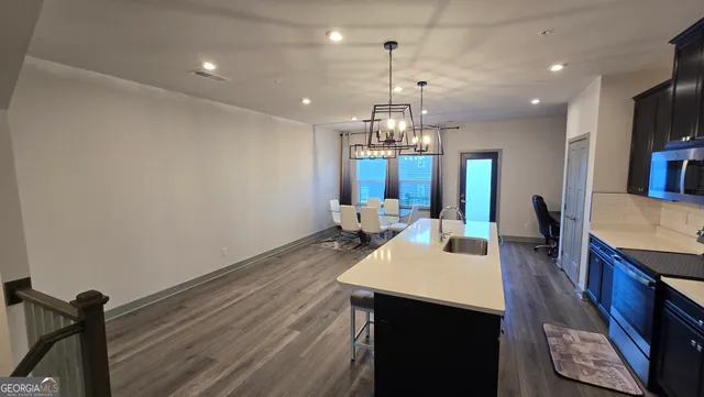 a large kitchen with a table chairs refrigerator and a wooden floor