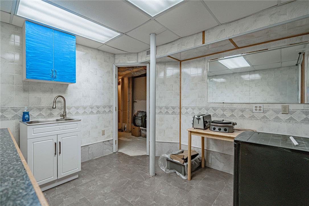 652 Old State Road Oley, PA 19547 - Photo 39 of 54 Functional basement utility area with tiled walls and a convenient sink, ready for various uses.