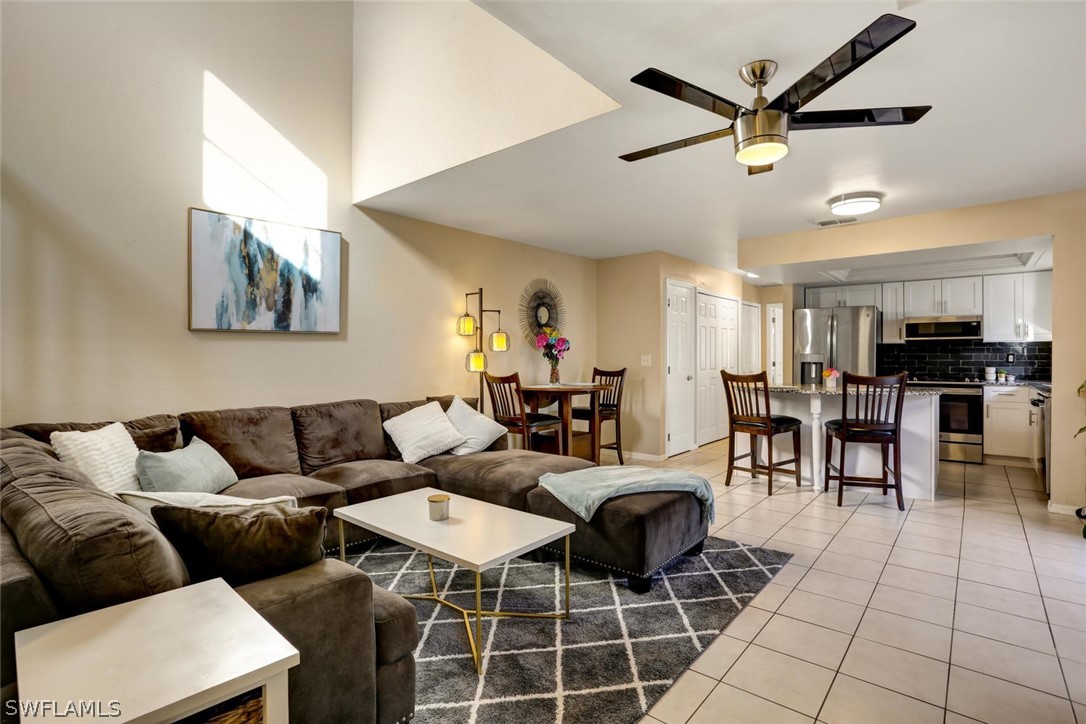 13710 Raleigh Lane, Unit 5 Fort Myers, FL 33919 - Photo 4 of 29 a living room with furniture a kitchen view and a chandelier