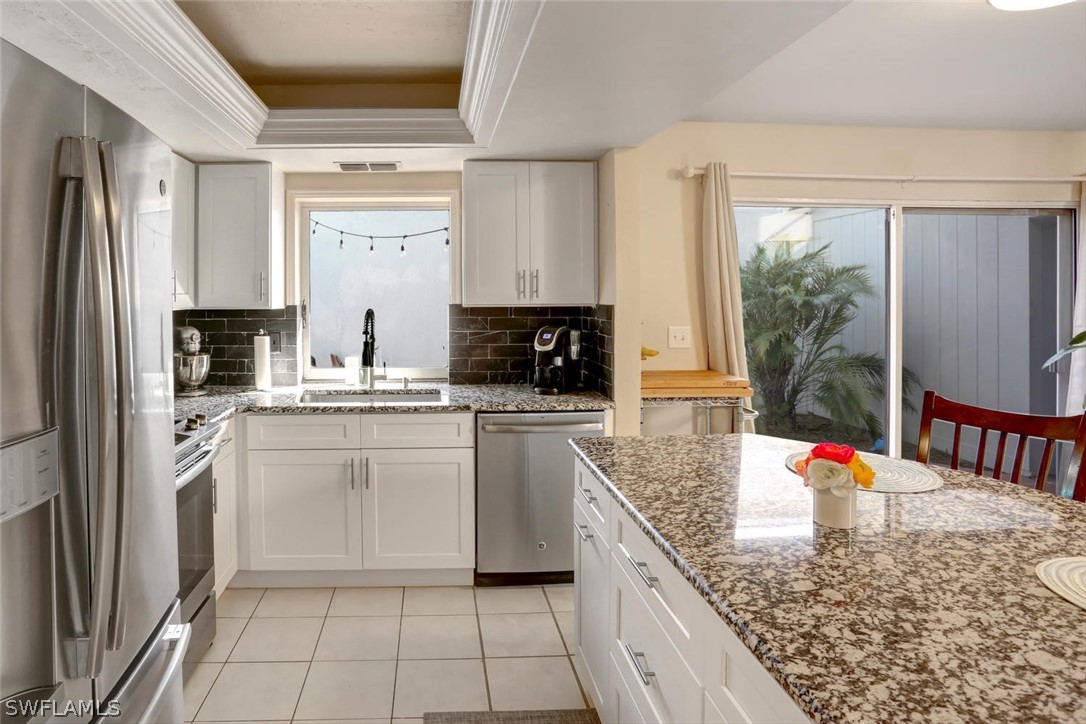 13710 Raleigh Lane, Unit 5 Fort Myers, FL 33919 - Photo 7 of 29 a kitchen with stainless steel appliances granite countertop a stove a sink and white cabinets