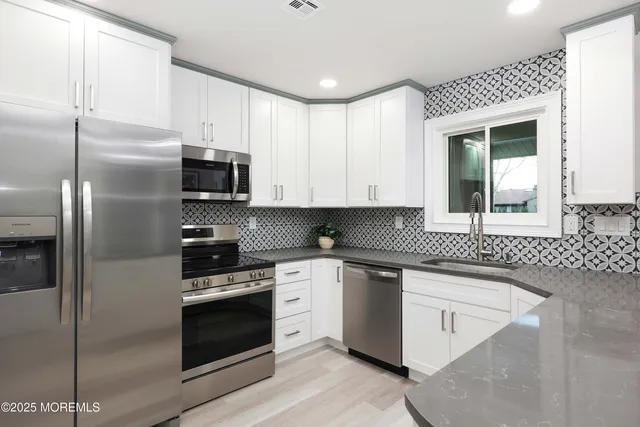 a kitchen with stainless steel appliances granite countertop a stove a sink and a refrigerator