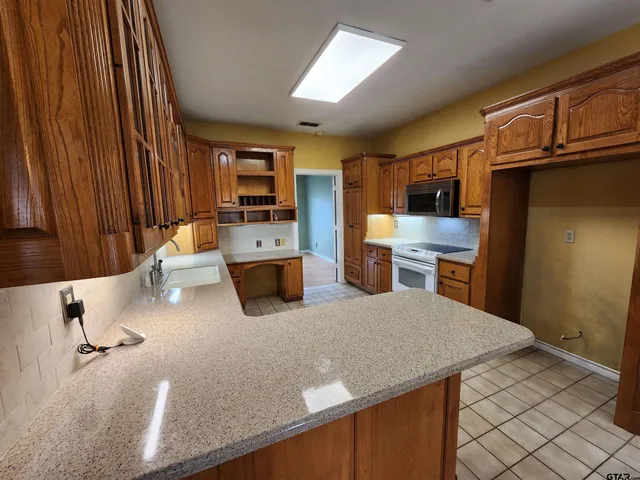 a kitchen with stainless steel appliances granite countertop a sink refrigerator stove and microwave