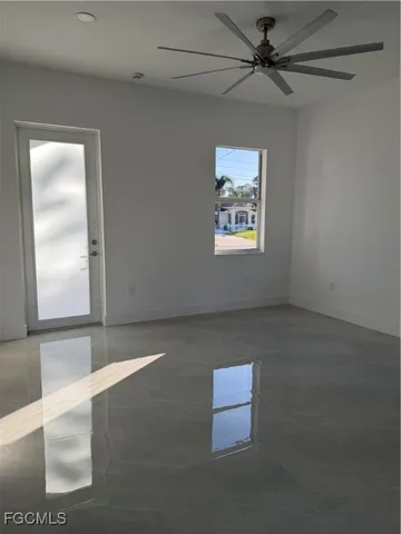 an empty room with windows and fan