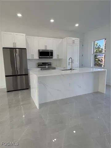 a large kitchen with stainless steel appliances a refrigerator and a stove top oven