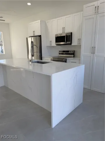 a large kitchen with stainless steel appliances granite countertop a refrigerator a stove and a sink