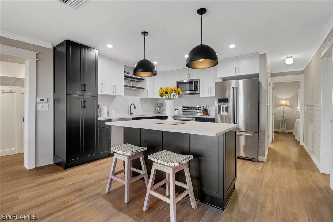 a kitchen with stainless steel appliances granite countertop a refrigerator a sink dishwasher a stove and a dining table with wooden floor