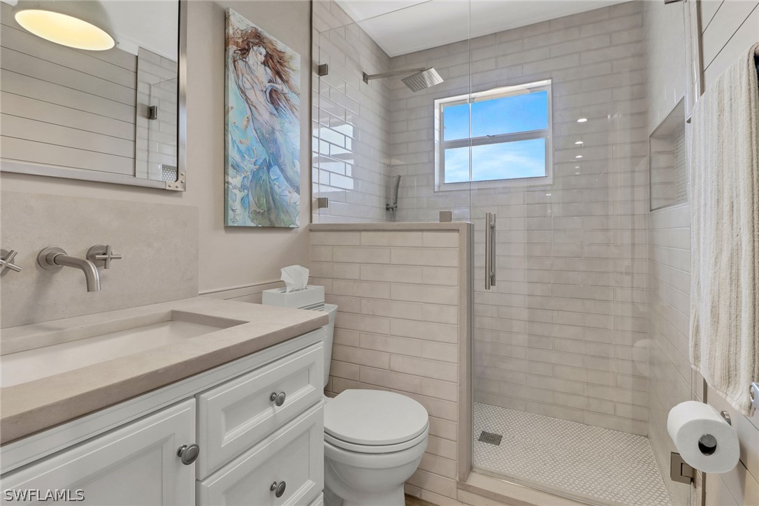 2574 Bayshore Drive Matlacha, FL 33993 - Photo 30 of 43 a bathroom with a granite countertop toilet a sink a mirror a window and a shower