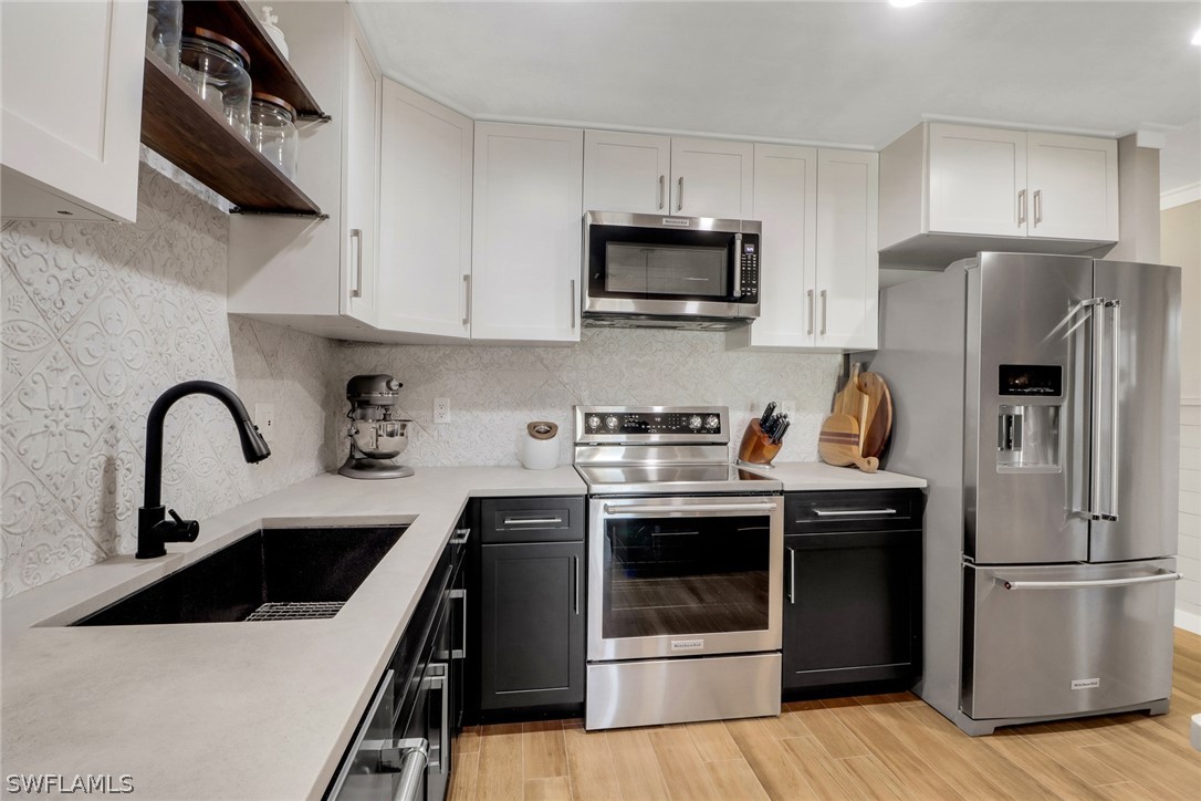 2574 Bayshore Drive Matlacha, FL 33993 - Photo 5 of 43 a kitchen with stainless steel appliances a sink a stove a microwave and cabinets