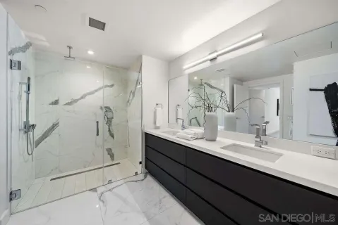 a bathroom with a double vanity sink mirror and shower