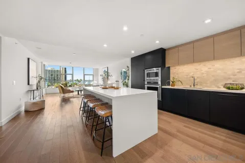 a living room with stainless steel appliances kitchen island granite countertop a refrigerator a stove top oven a dining table and chairs with wooden floor