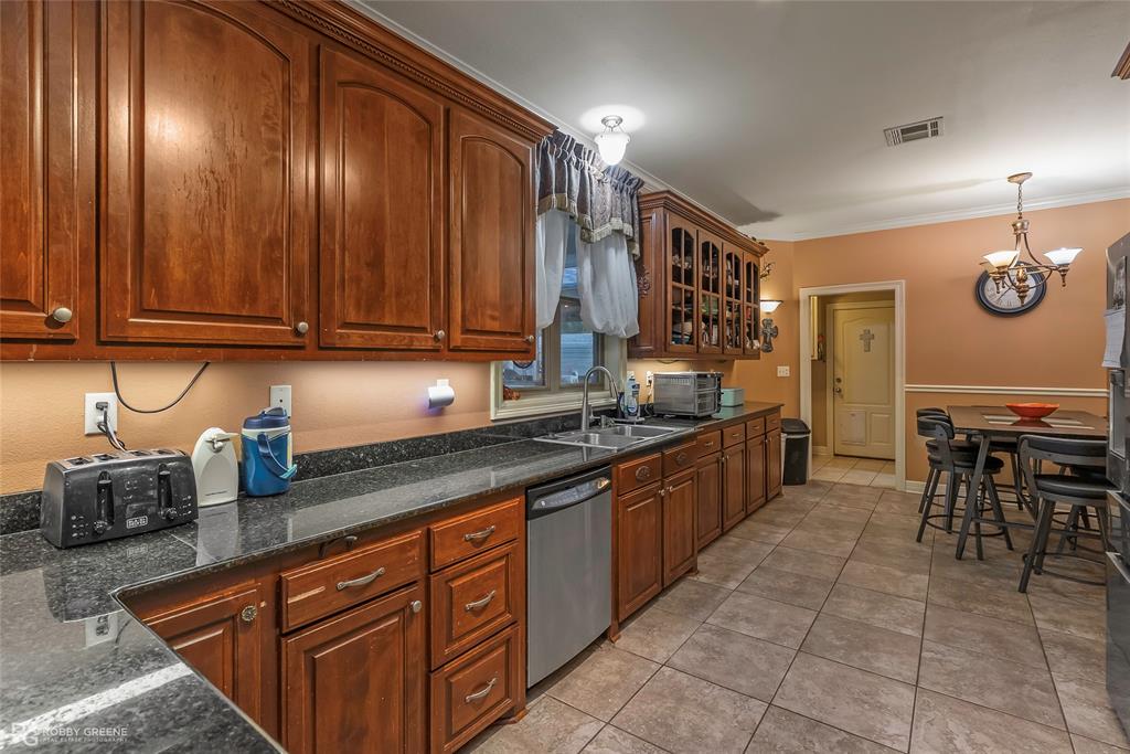 12168 Highway 157 Princeton, LA 71067 - Photo 17 of 32 Kitchen with stainless steel dishwasher, glass insert cabinets, light tile patterned flooring, ornamental molding, and a chandelier