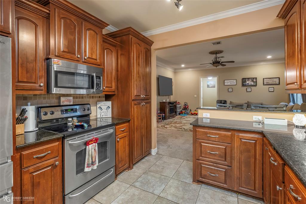 12168 Highway 157 Princeton, LA 71067 - Photo 20 of 32 Kitchen featuring appliances with stainless steel finishes, crown molding, decorative backsplash, a peninsula, and ceiling fan