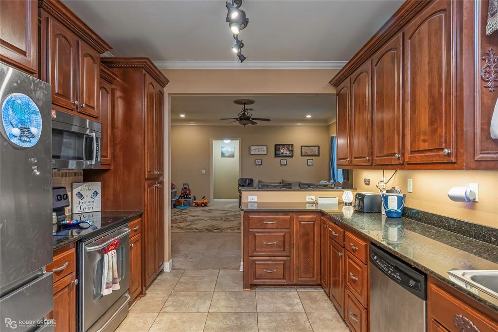 12168 Highway 157 Princeton, LA 71067 - Photo 23 of 32 Kitchen featuring stainless steel appliances, a peninsula, dark stone countertops, ceiling fan, and ornamental molding
