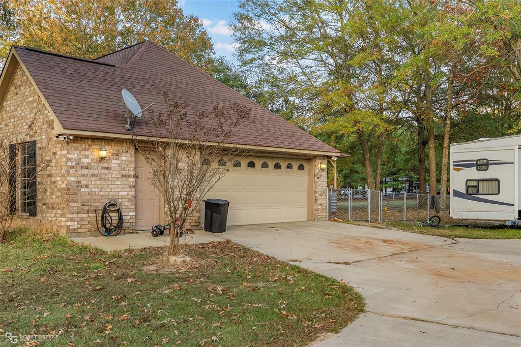 12168 Highway 157 Princeton, LA 71067 - Photo 4 of 32 View of home's exterior featuring brick siding, a shingled roof, concrete driveway, and a garage