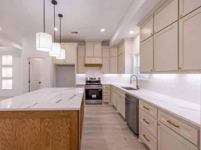 a kitchen with kitchen island granite countertop a sink a counter space appliances and cabinets