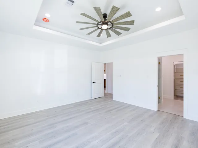 an empty room with wooden floor and ceiling fan