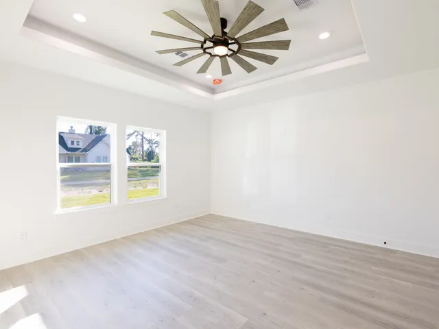 an empty room with windows and fan