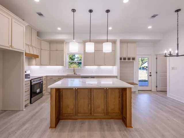 a kitchen with kitchen island a wooden floor stainless steel appliances and window